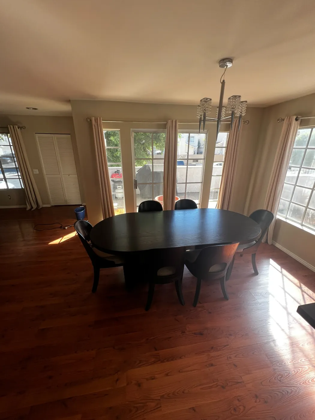 Residential dining room with a dark table, hardwood floors, and sunlit windows