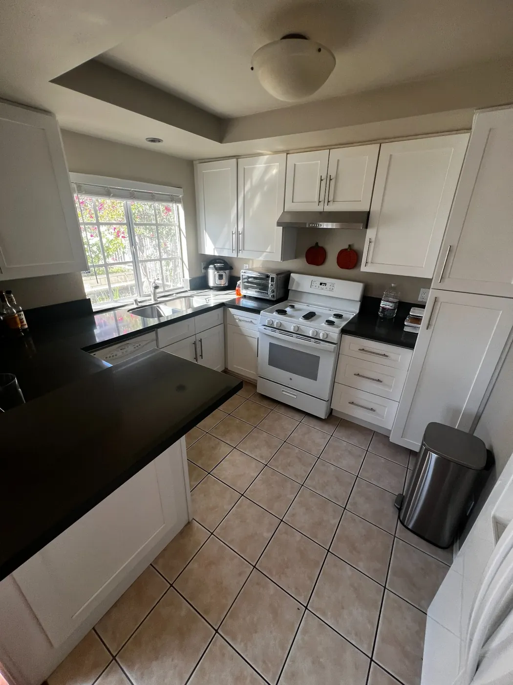 Residential kitchen with white cabinetry, black countertops, and tiled flooring